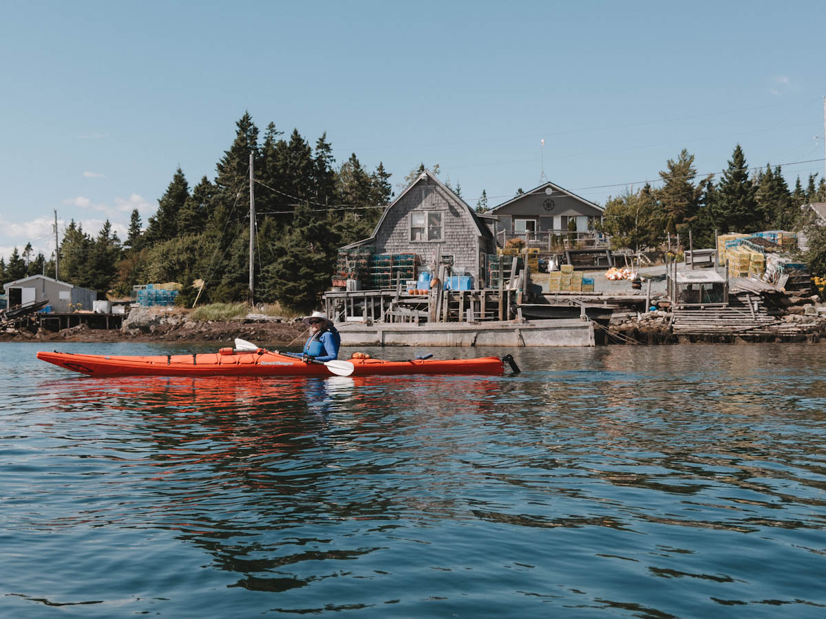 Kayak sur l'eau devant une belle demeure  côtiere à Cape LaHave adventures