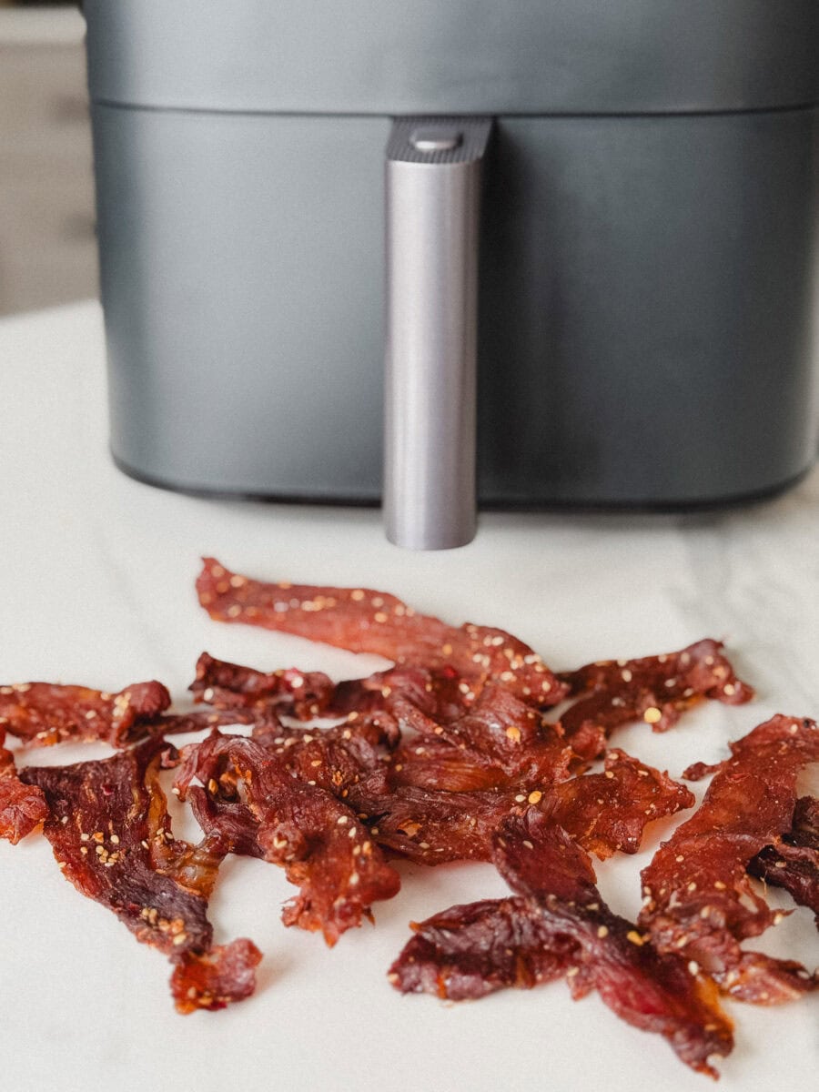 jerky de porc devant un air fryer sur comptoir blanc