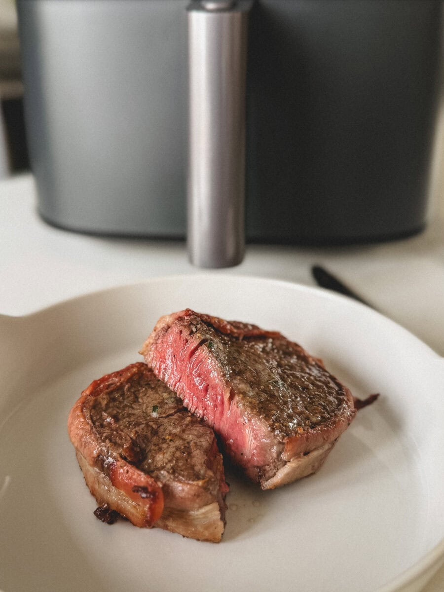 tournedos de boeuf grillé bardé de bacon, coupé en deux saignant à l'intérieur, devant panier du air fryer