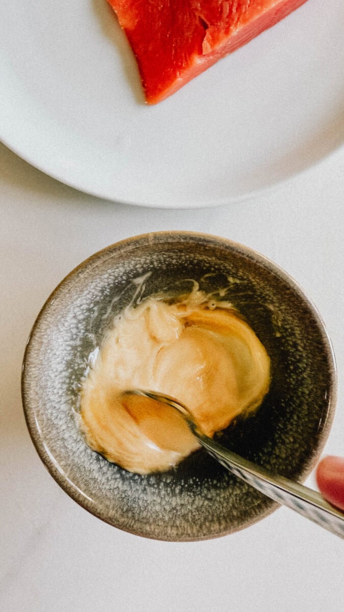bol de sauce qui se fait mélanger à la cuillère avec bout de saumon cru dans assiette à côté