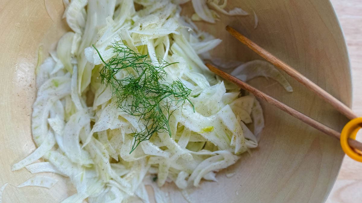 salade de fenouil dans u bol avec pinces de service en bois