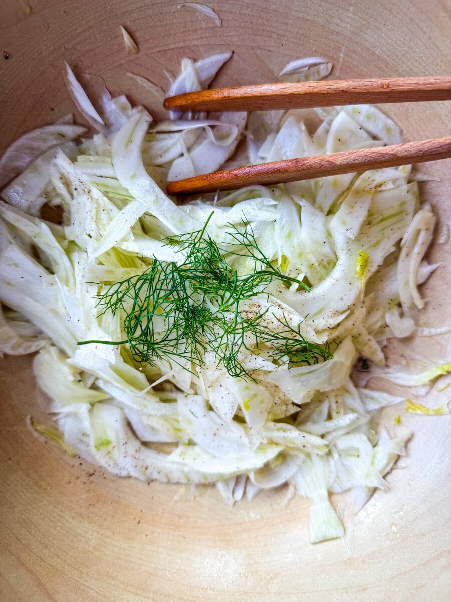 salade de fenouil dans un bol en bois avec pinces de service en bois