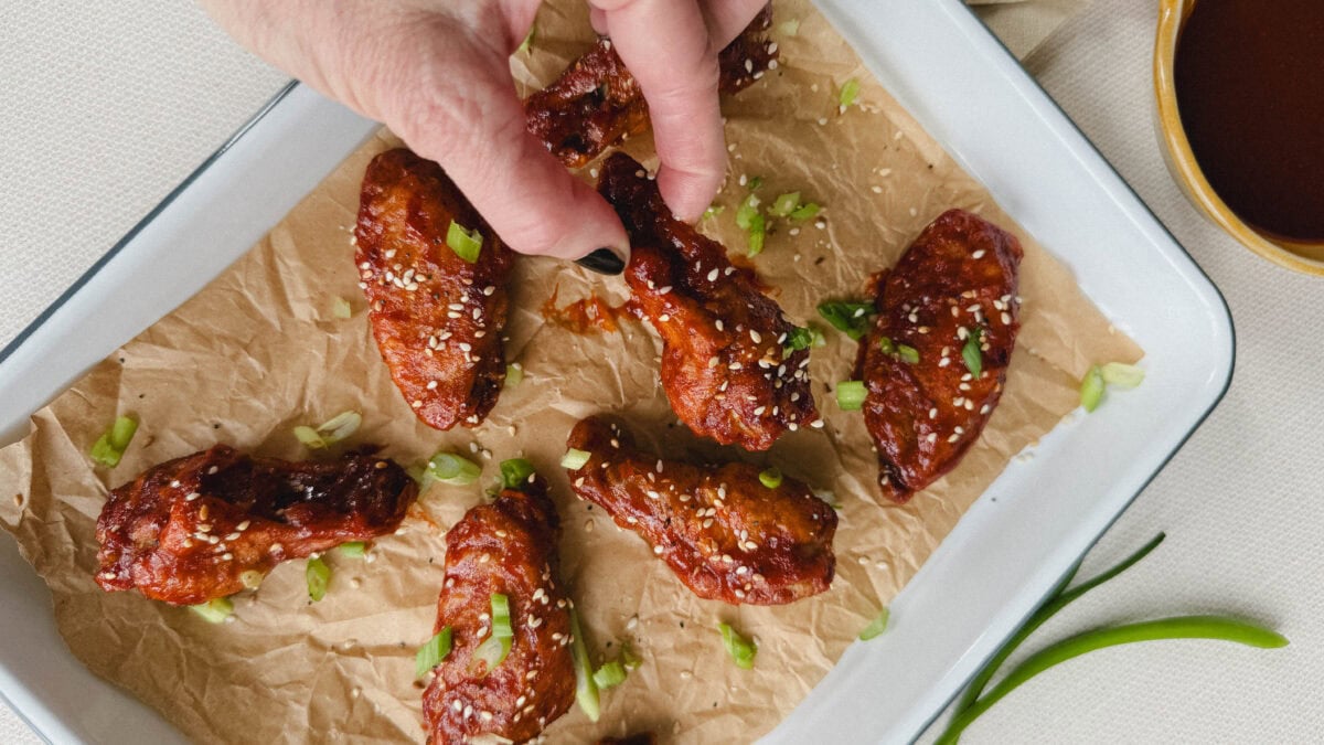 main qui prend une aile de poulet glacée dans un plateau d'ailes de poulet