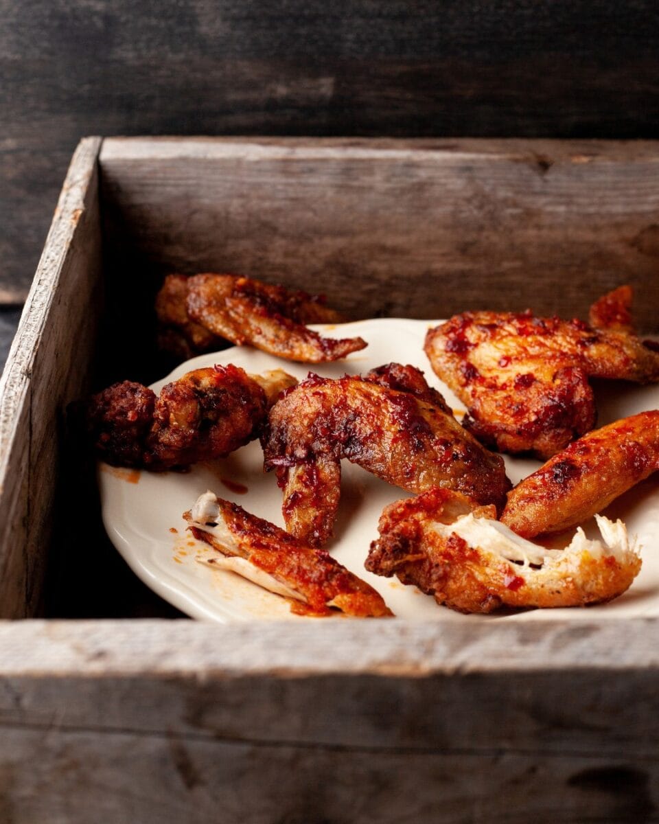 ailes de poulet grillées dans une assiette blanche dans boite de bois
