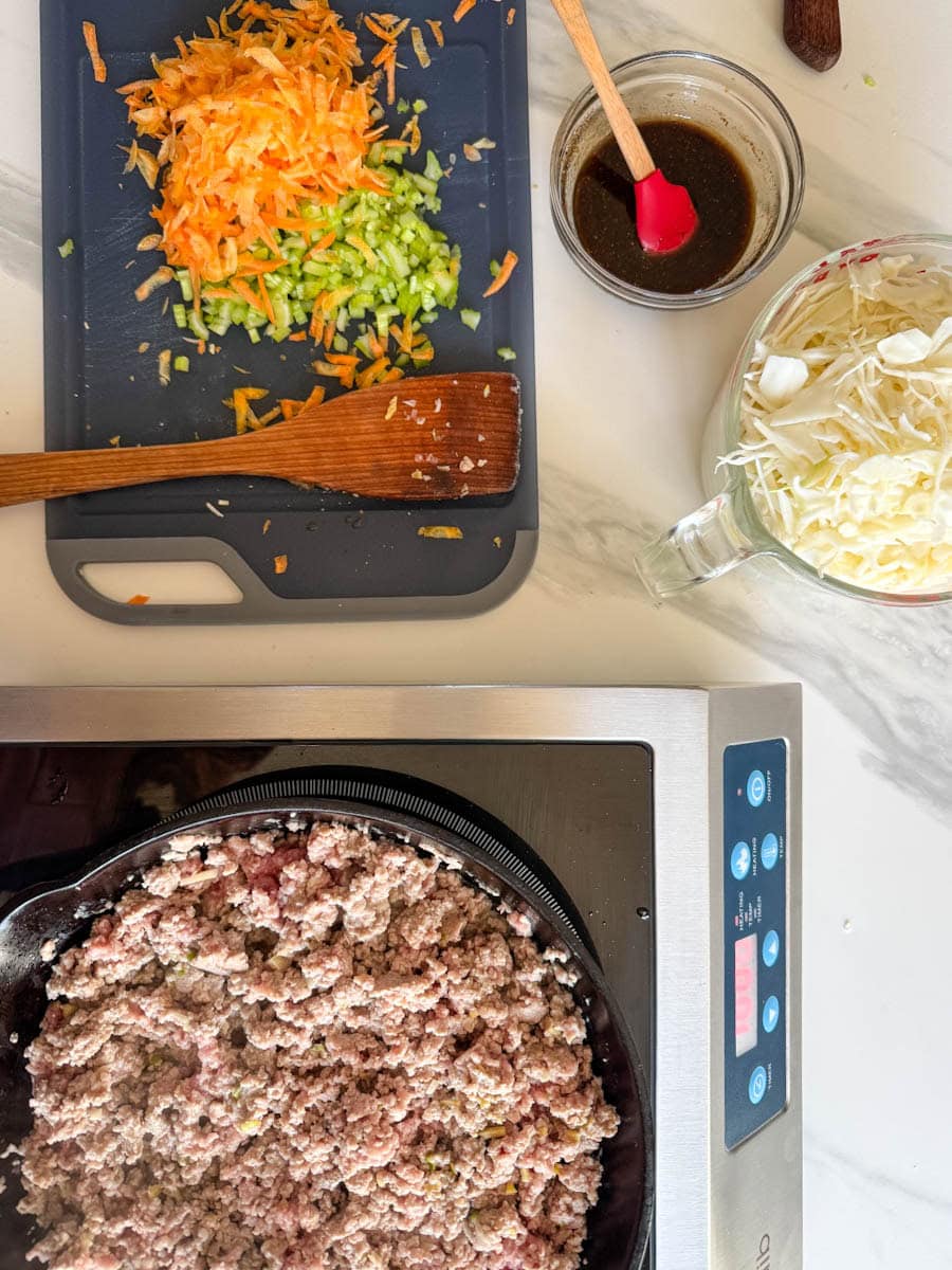 viande dans poêlon, légumes hachés sur planche et sauce dans un bol