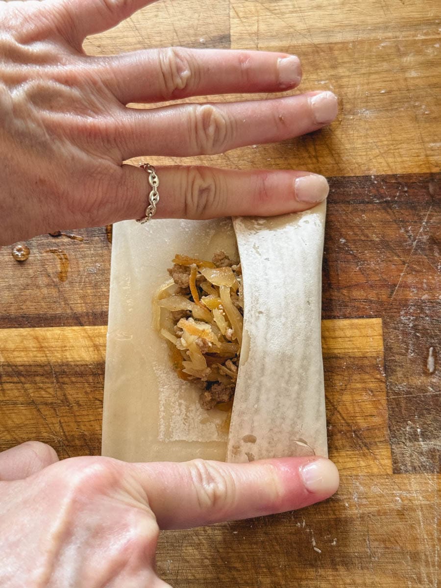 mains qui replient la pâte à pâté impérial sur la farce