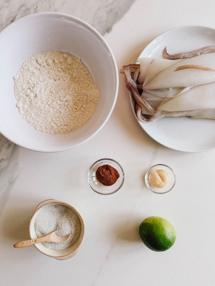 ingrédients sur le comptoir: calmars entier, farine, sel, paprika, ail en poudre et citron vert