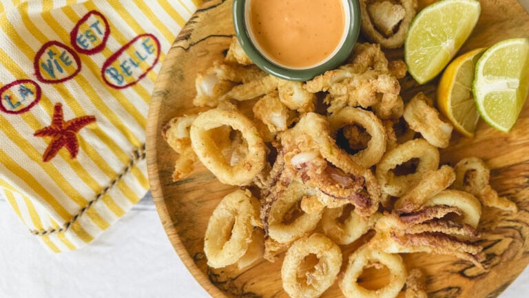 calmars frits dans une assiette en bois avec quartiers de citron et lime et linge de table :la vie est belle