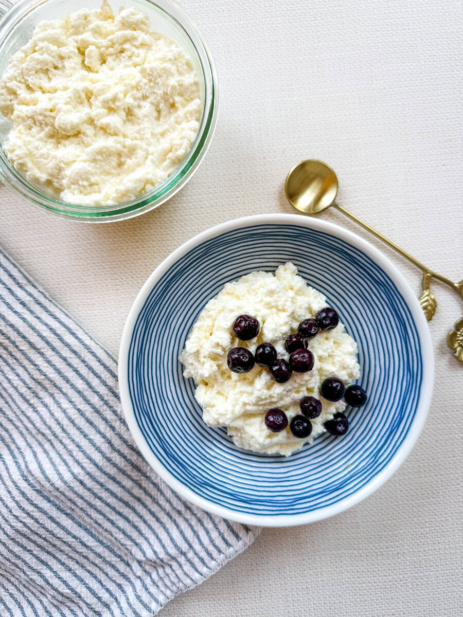 fromage cottage fait. maison dans un bol avec bleuets et petit bol de fromage frais à côté