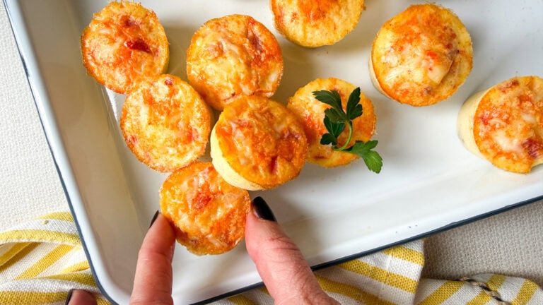 main qui tient une bouchées aux oeufs sur un plateau blanc