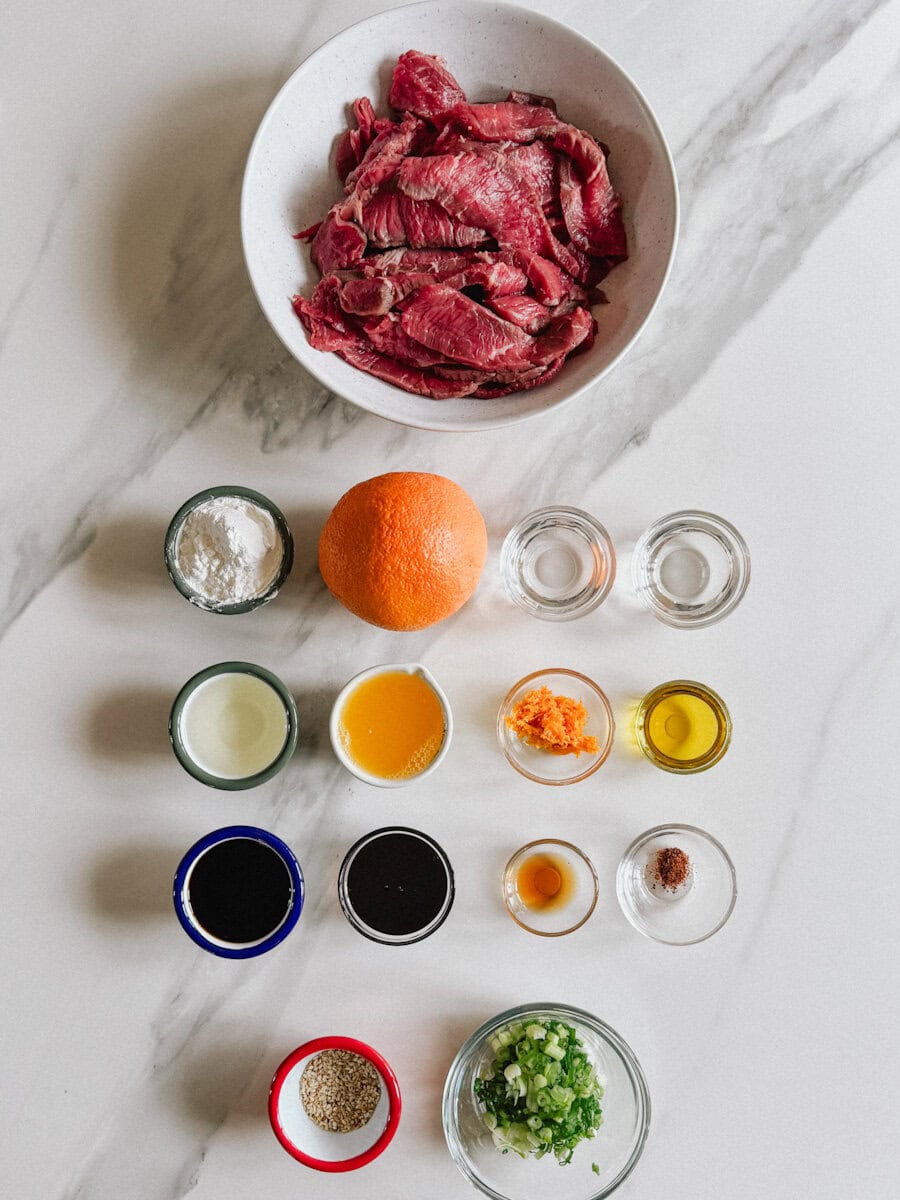 ingrédients pour boeuf à l'orange dans des petits pots et bols sur comptoir marbré blanc