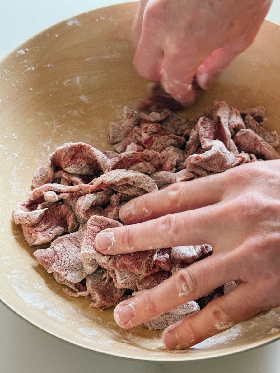 mains combinant lanières de boeuf et fécule dans un bol en bois