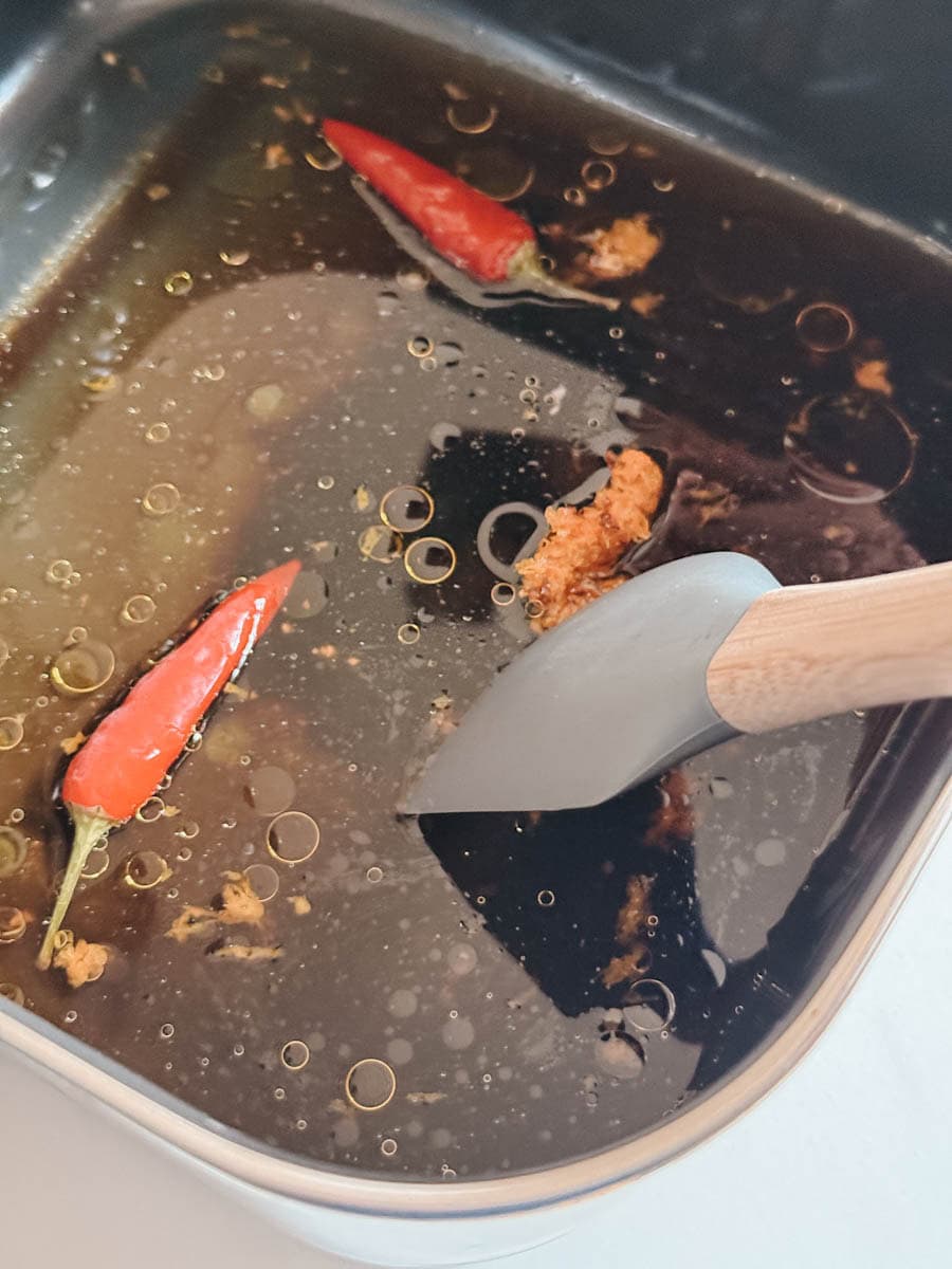 sauce boeuf à l'orange dans un panier de air fryer avec spatule qui combine les ingrédients