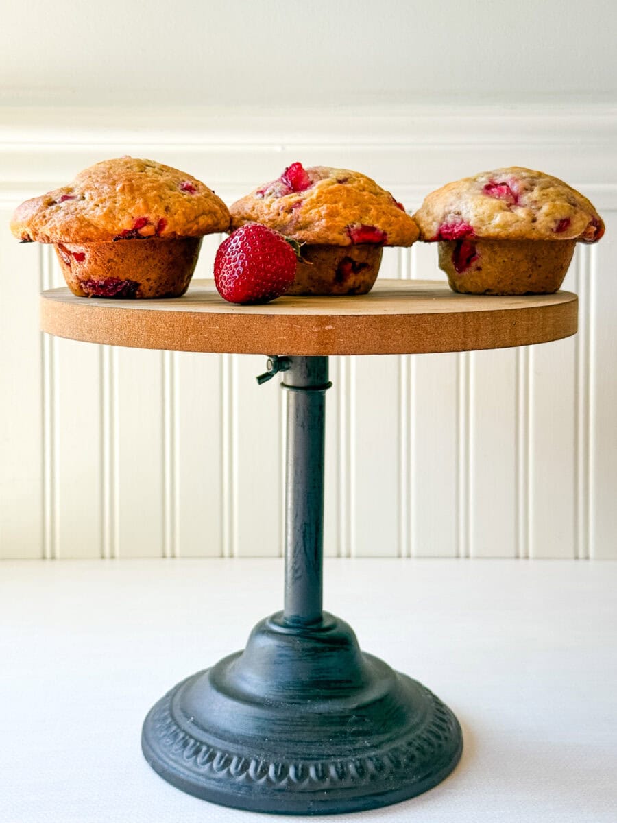 3 muffins aux fraises sur un support à gâteau en bois et fonte