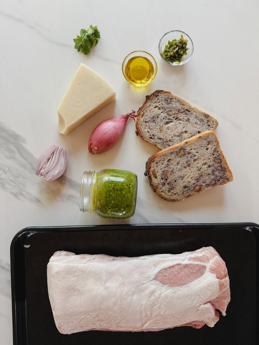 ingrédients sur comptoir blanc marbré: longe de porc, pain, pesto, fromage, huile olive, assaisonnements