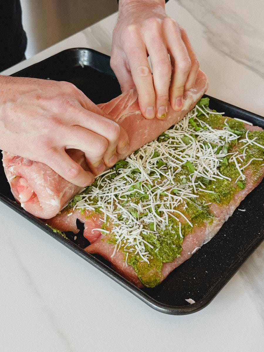 mains qui roulent une longe de porc farcie