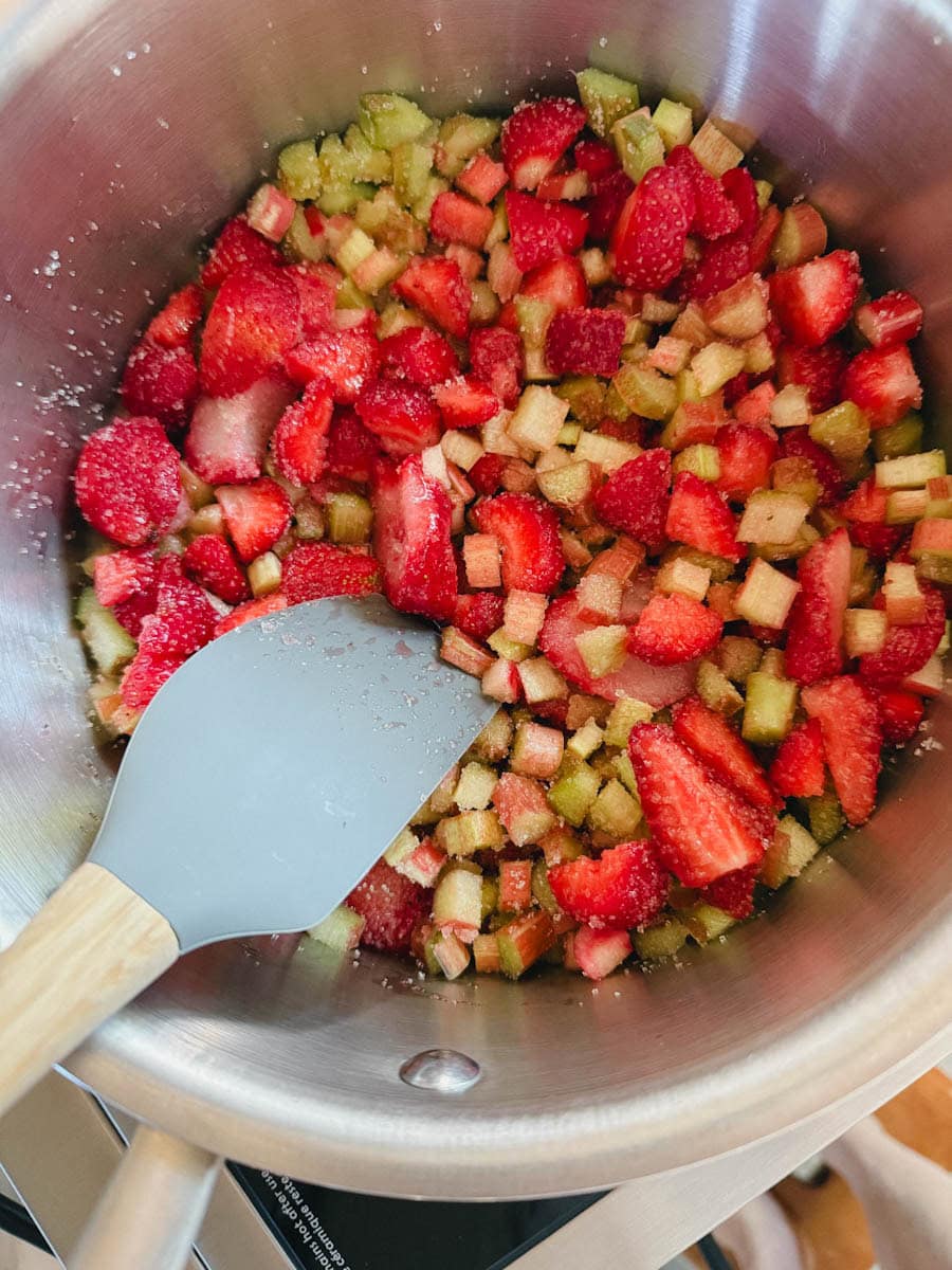 casserole avec fraises et rhubarbes et sucre et maryse qui mélange