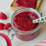pot de confiture de framboise avec framboises fraîches et toast à la confiture en arrière plan