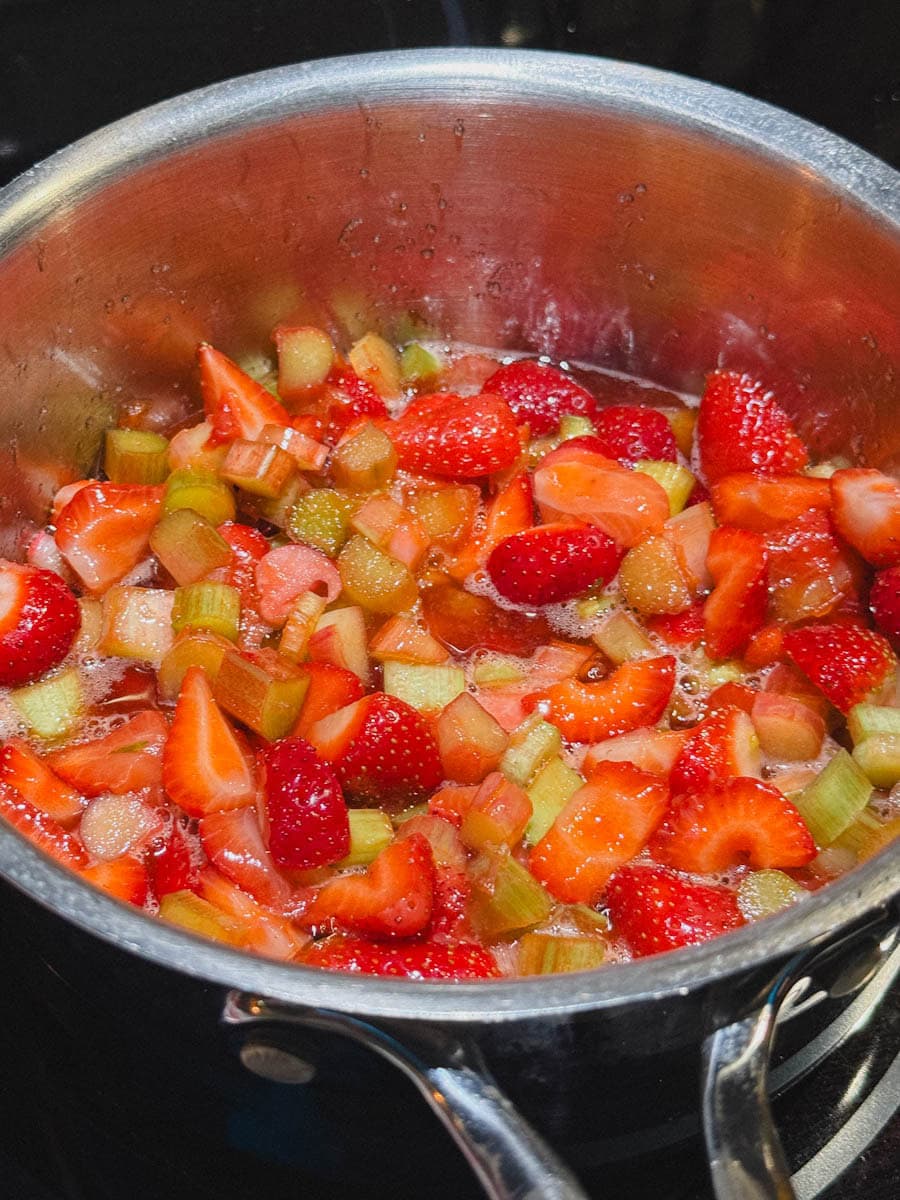 fraises et rhubarbe qui cuisent dans leur sirop dans une casserole