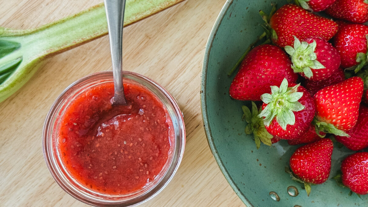 pot de confiture fraise rhubarbe avec rhubarbe et fraises fraiches sur comptoir en bois blond