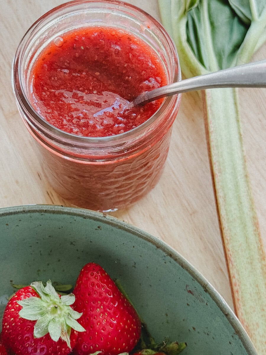 pot de confiture fraise rhubarbe avec fraises fraîches et tige de rhubarbe sur comptoir en bois