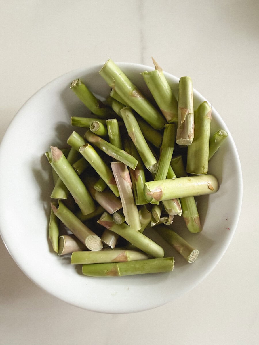 queues d'asperges dans un bol blanc sur comptoir marbré blanc