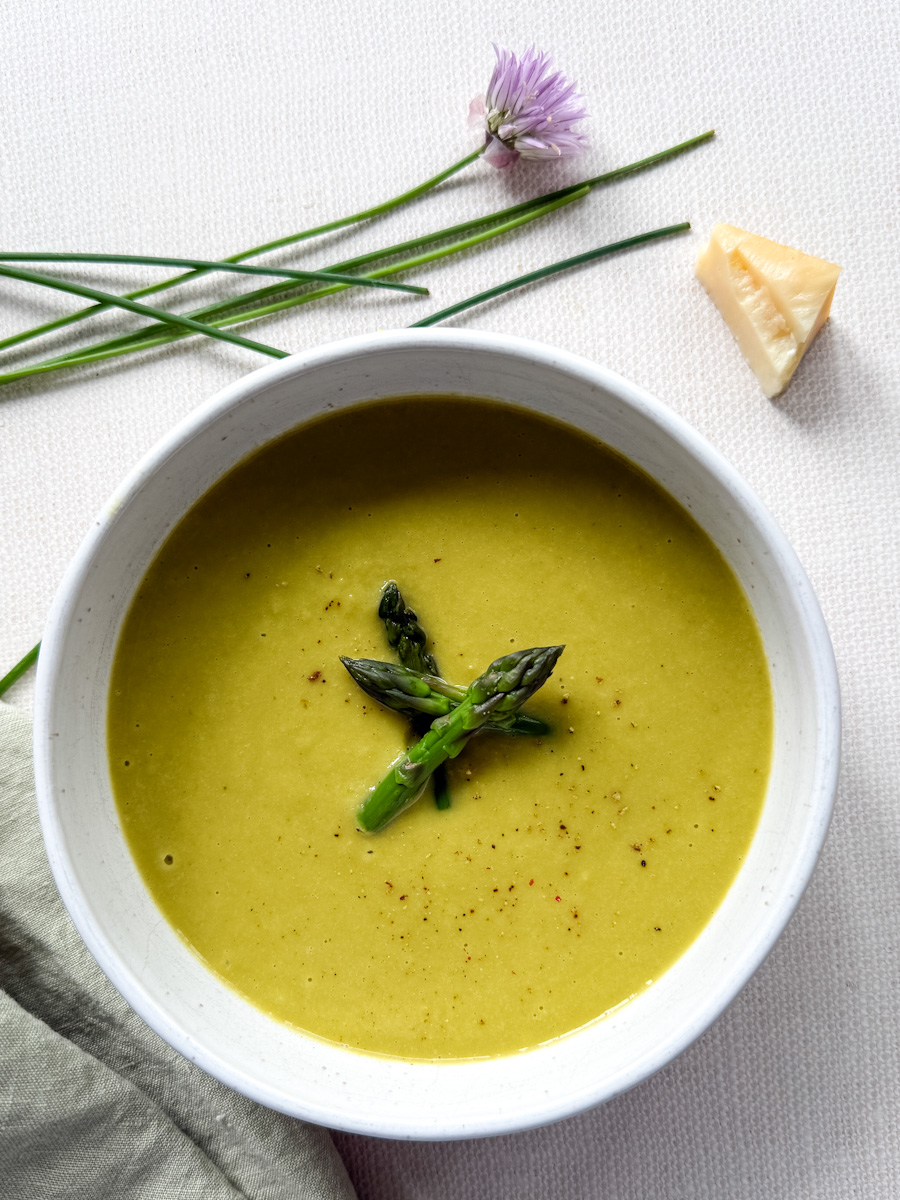 crème d'asperges et artichauts dans un bol blanc avec fleur de ciboulette