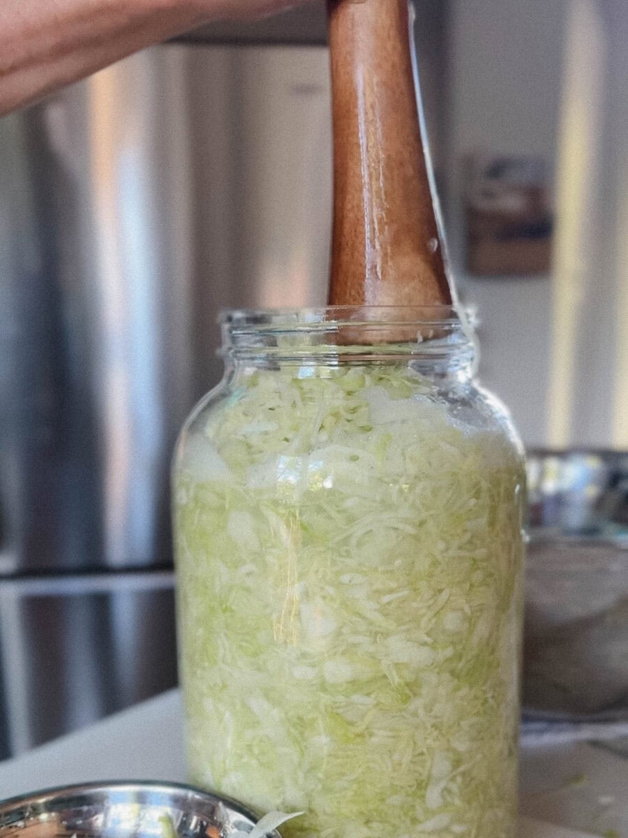 pot de verre avec pilon en bois qui presse du chou en lanières