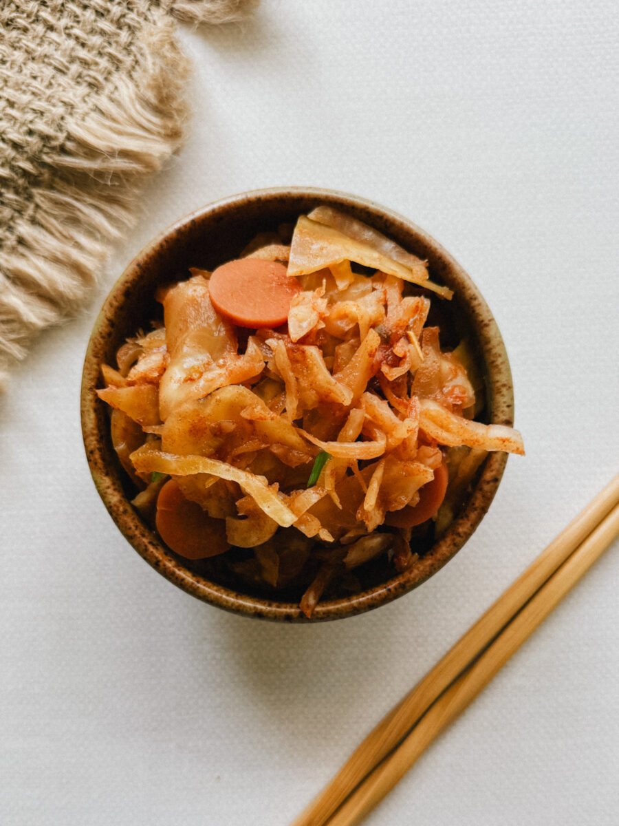 bol de kimchi avec baguettes chinoises sur table blanche avec nappe de jutte sur le côté