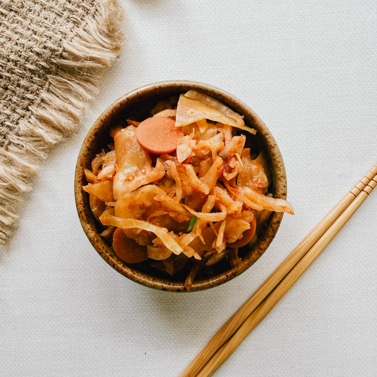 bol de kimchi sur table beige avec chopsticks et linge en lin naturel
