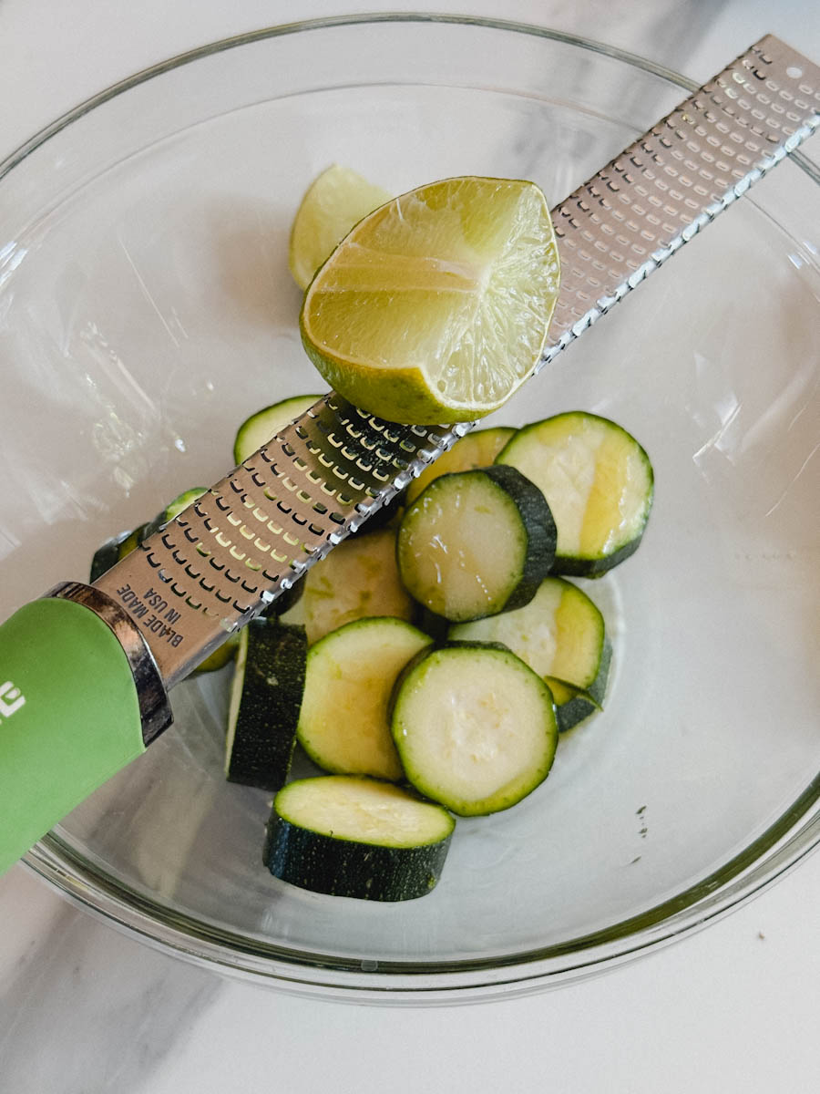 rondelles de courgette air fryer dans un bol, zesteur avec lime sur le bol
