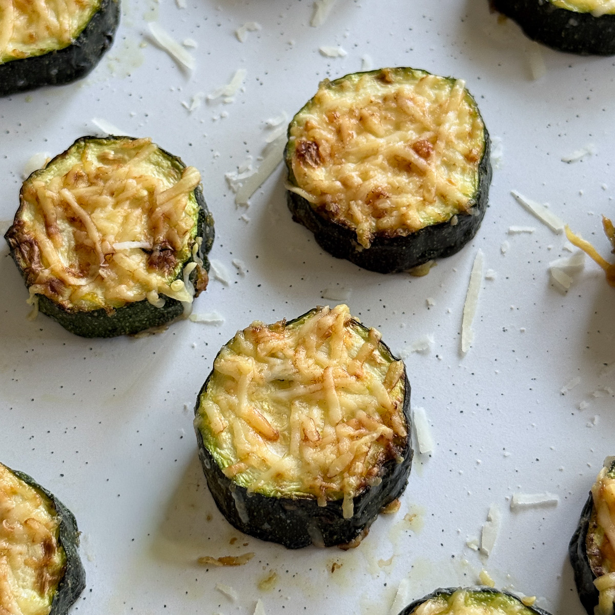 rondelles de courgettes gratinées dans une assiette blanche tachetée