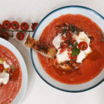 deux bols de soupe froide de tomate avec burrata, garniture de tomate fraiche, crouton de pain sur table pâte avec tomates cerises sur branche
