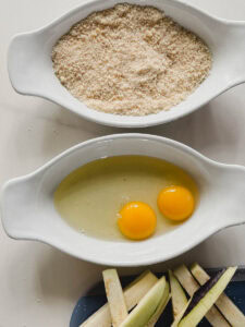 deux bols pour panure, bol avec 2 oeufs et bol avec chapelure et assiette avec lanières d'aubergine