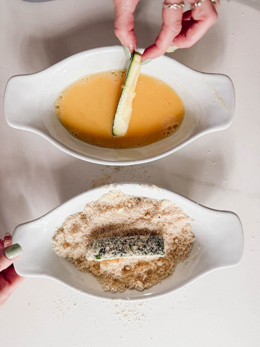 deux bols, un avec oeuf et un avec chapelure et lanière de courgette dans chacun
