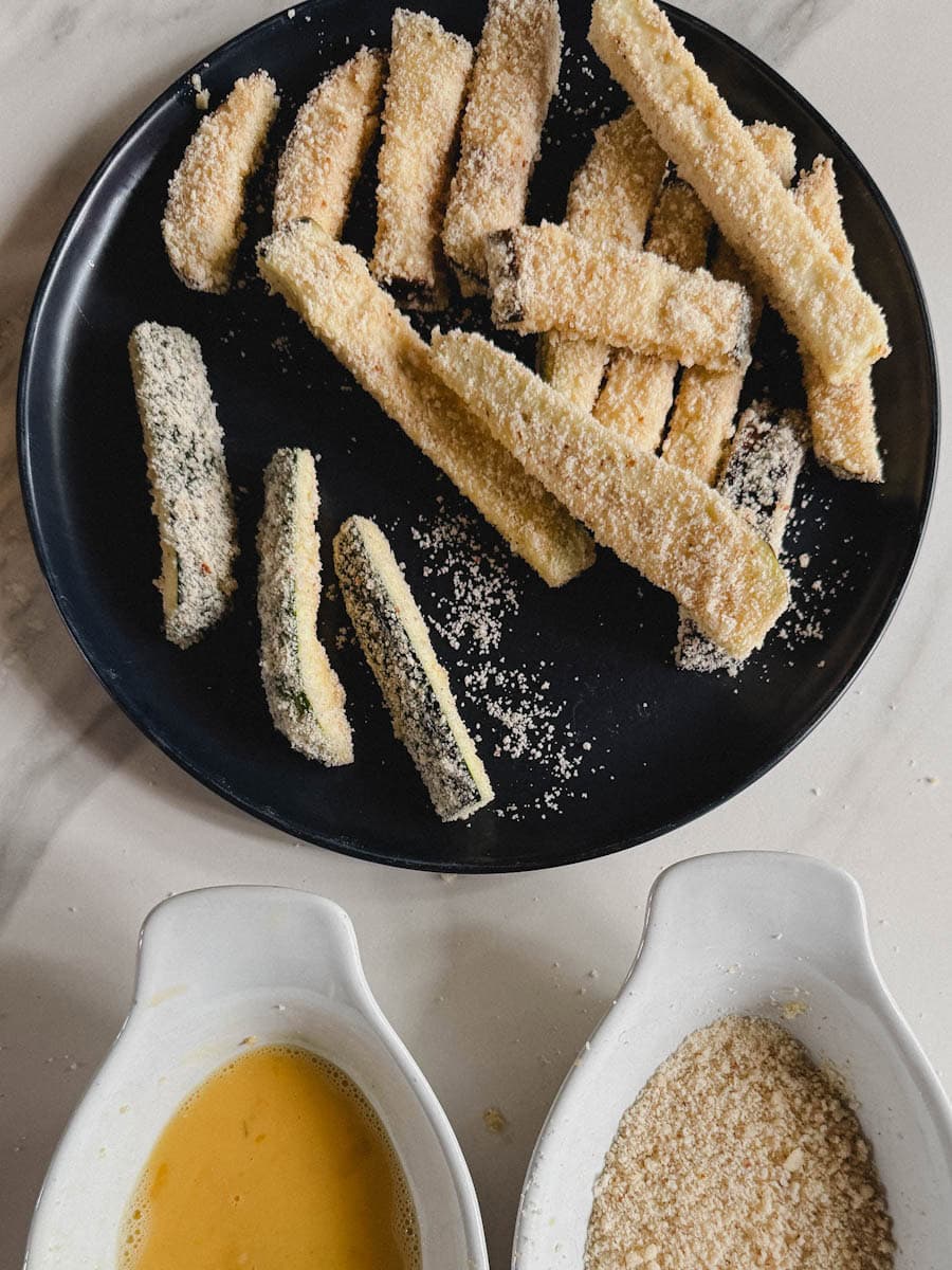 deux bols pour panure, bol avec 2 oeufs et bol avec chapelure et assiette avec lanières d'aubergine