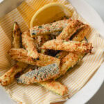 frites de courgettes panées croustillantes dansun bol sur napkin en papier lignée jaune et blanc