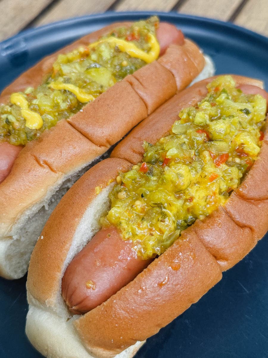 deux hot dogs avec relish sur le dessus dans une assiette bleue
