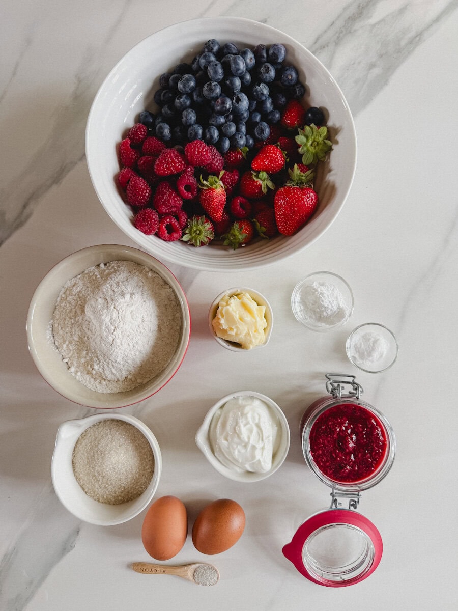 ingrédients sur comptoir marbré blanc: pot de framboises, bleuets et fraises fraîches, et autres ingrédients 