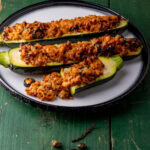 courgettes farcies à la viande dans une assiette blanche sur table en bois verte