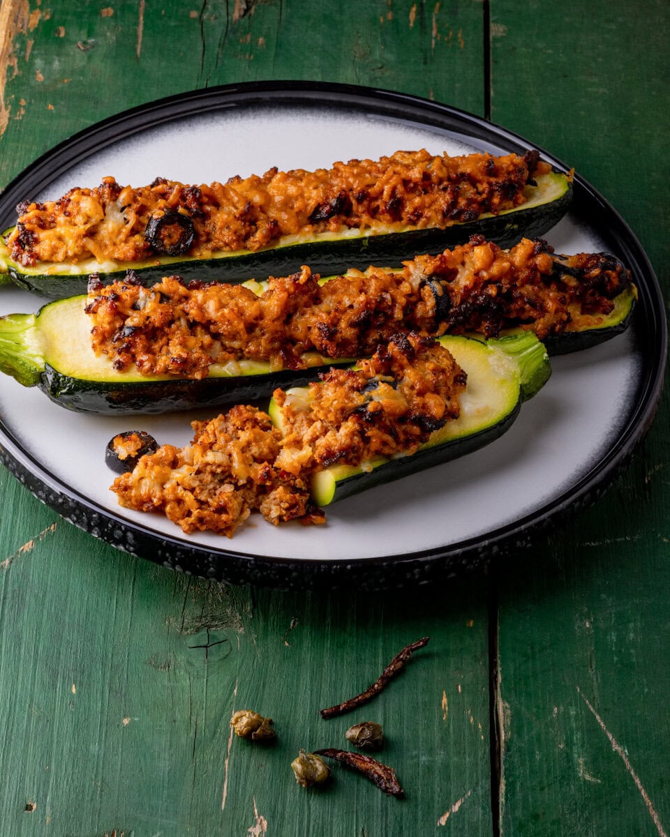 courgettes farcies à la viande dans une assiette blanche sur table en bois verte