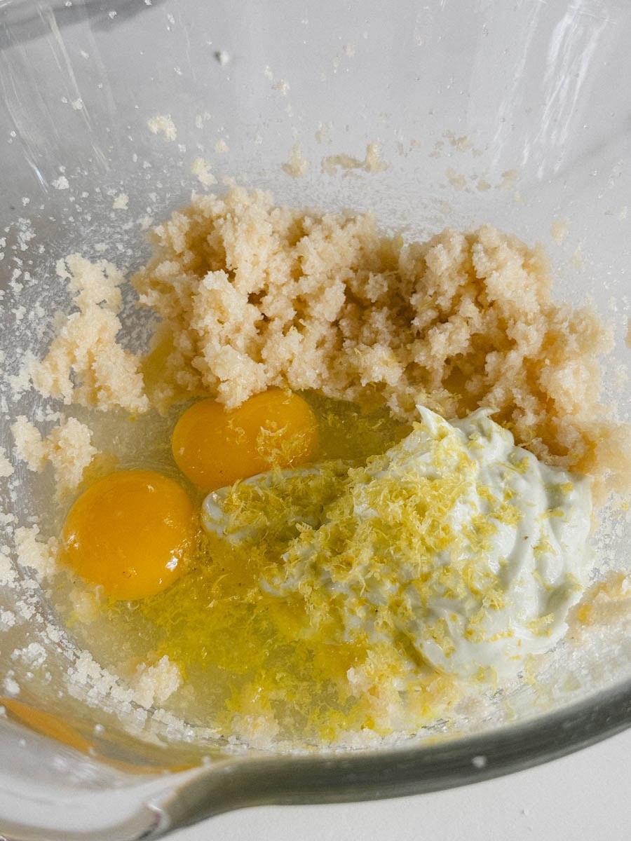 grand bol en verre avec pâte à muffin, oeufs, yogourt, zeste de citron prêt à être mélangés