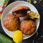 trois énormes muffins aux courgettes dans une assiette blanche avec citron et courgette sur le côté