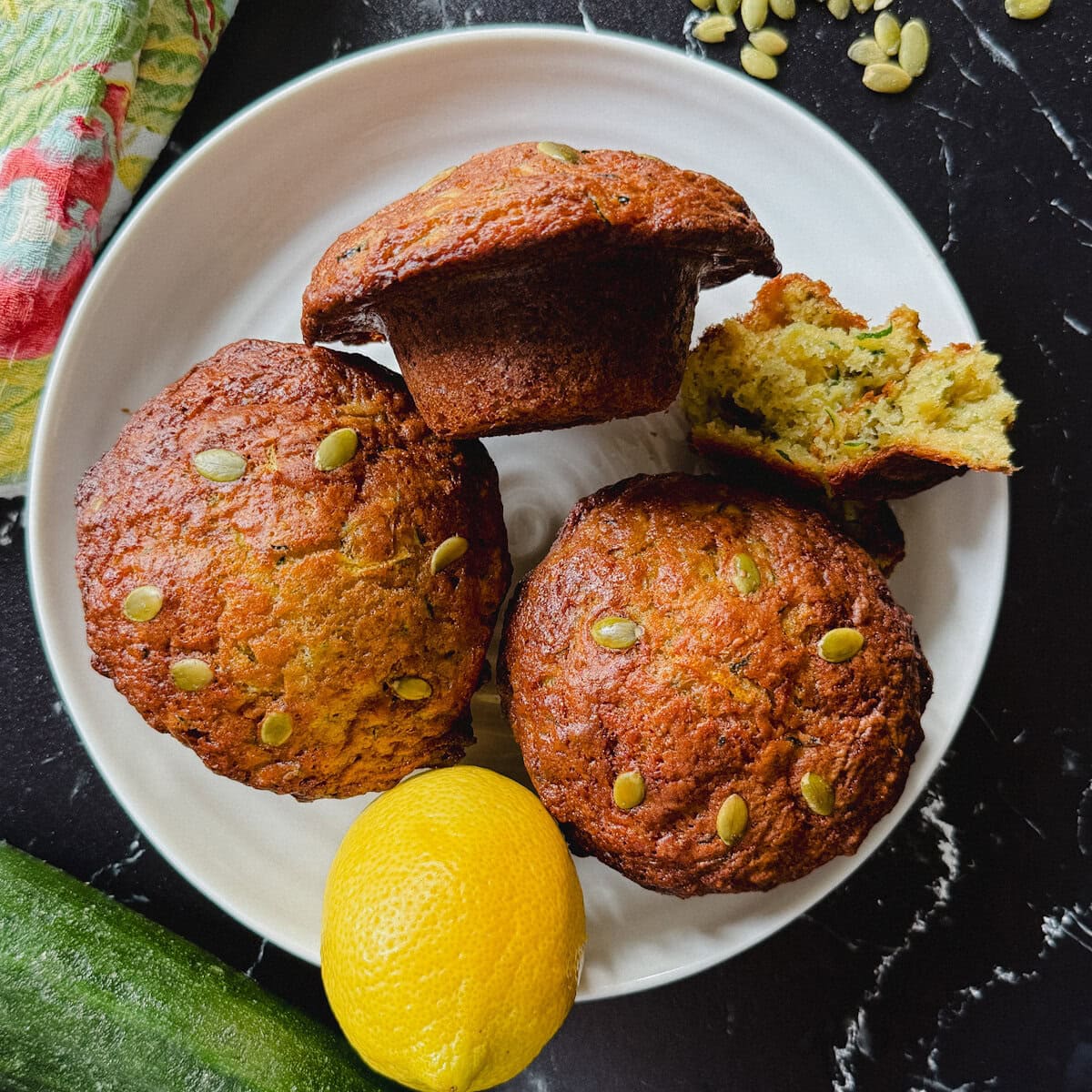 trois énormes muffins aux courgettes dans une assiette blanche avec citron et courgette sur le côté