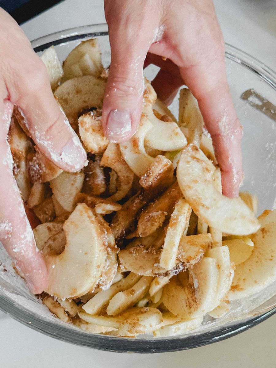mains qui mélangent pommes avec sucre et fécule