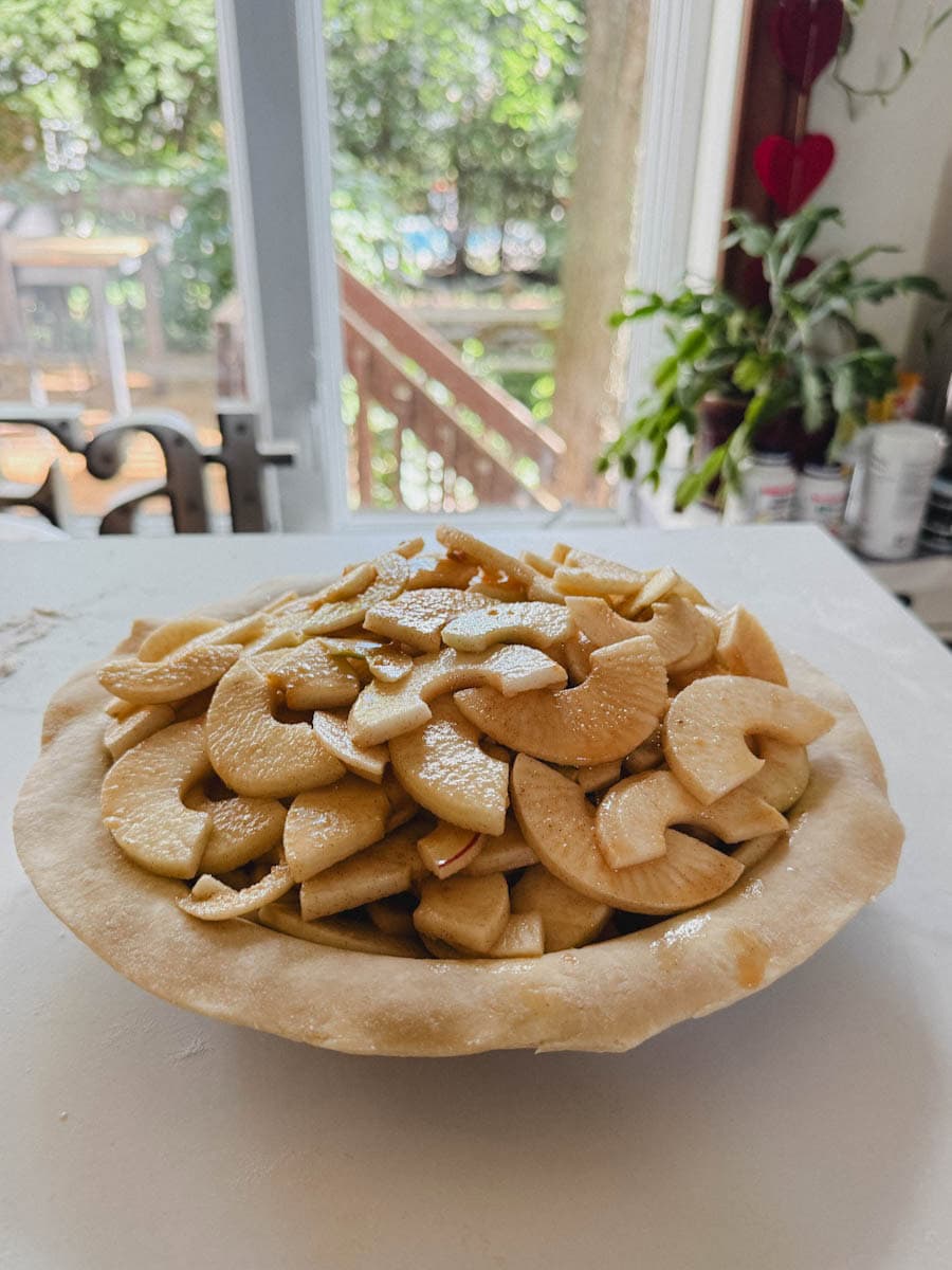 tarte aux pommes non cuite, montagne de pommes sur abaisse de pâte
