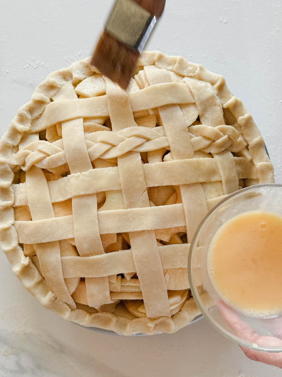 pinceau qui badigeonne une tarte au pomme de dorure à l'oeuf