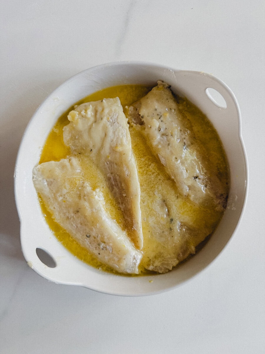 filets de morue fariné en sauce au beurre et citron dans un plat à gratin blanc pour le four
