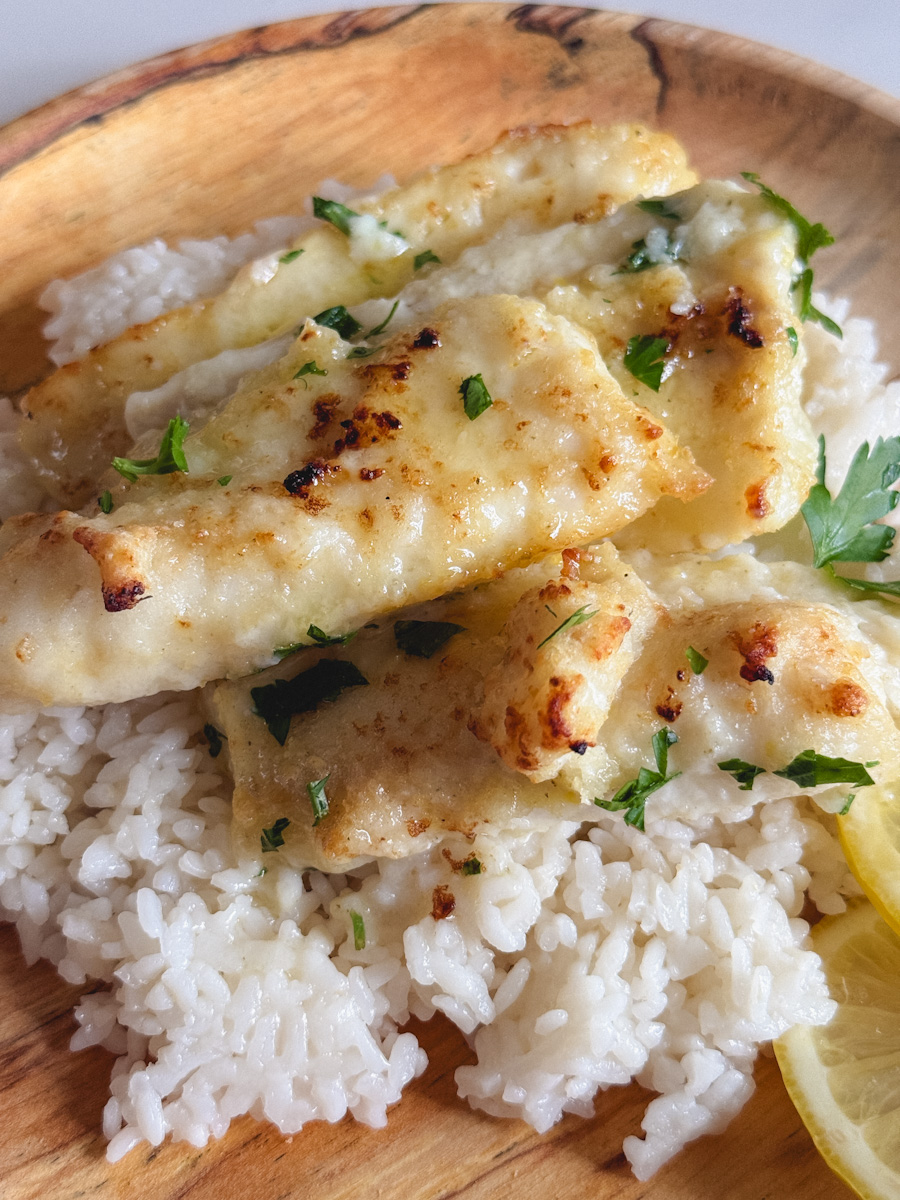 morue grillé sauce au beurre et citron sur riz dans une assiette en bois