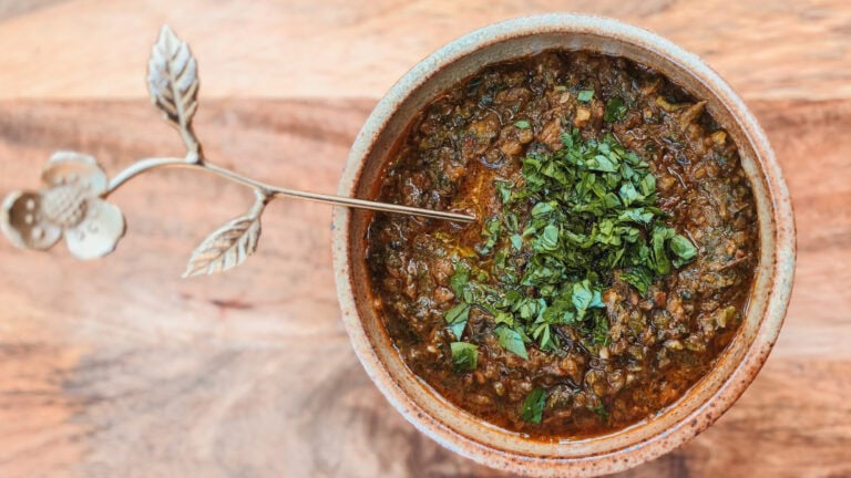 chimichurri de légumes grillés dans un bol sur planche de bois avec cuillère en couleur dorée